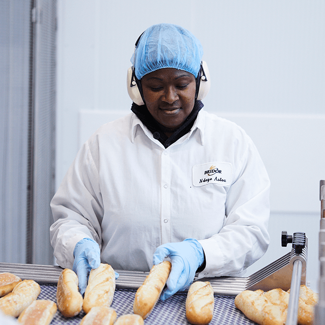 Employee turning baguette bread on a ligne