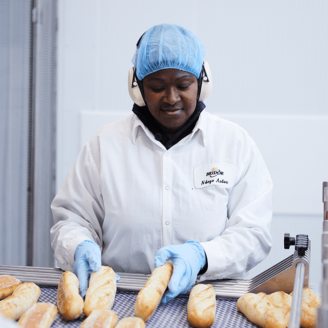 Employée qui tourne des baguettes sur une ligne