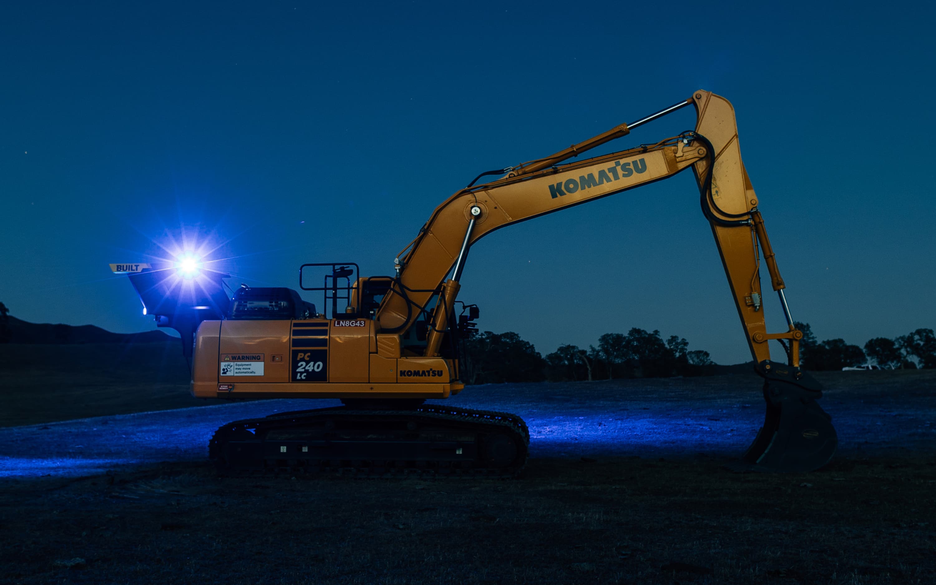 Nighttime beaming light on excavator