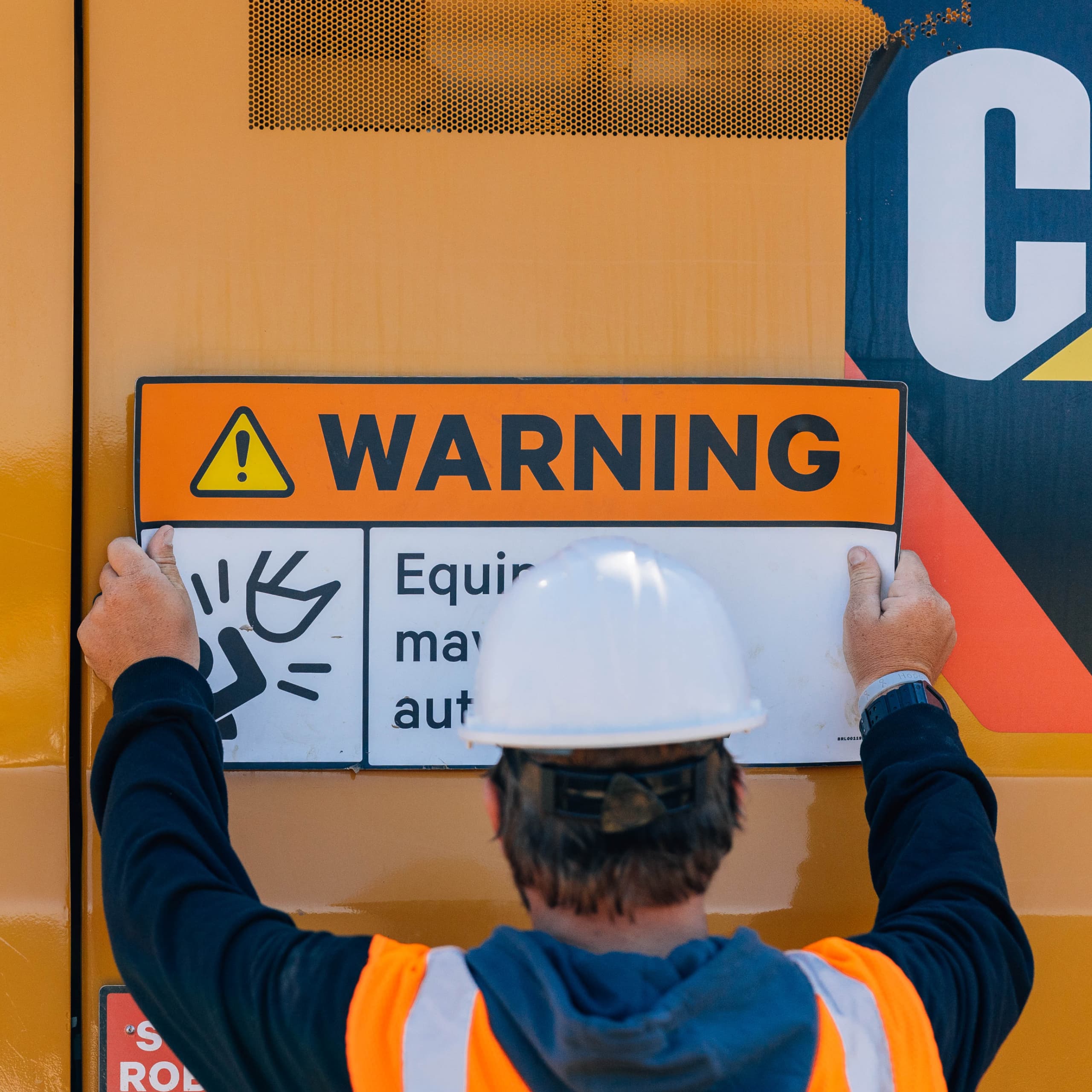 Reo attaching warning signs on excavator