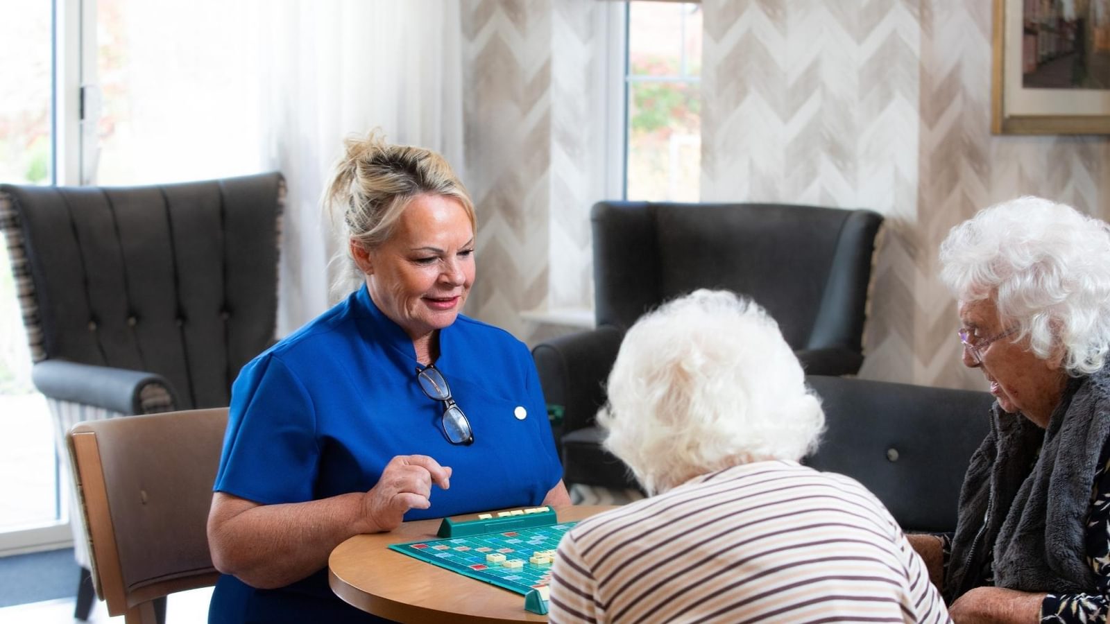 Nurse playing a board game with residents in the lounge