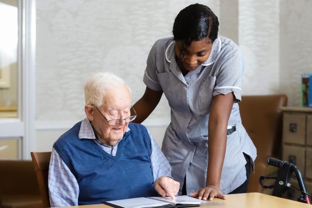 Carer at Caring Homes Group care home speaking to an elderly resident