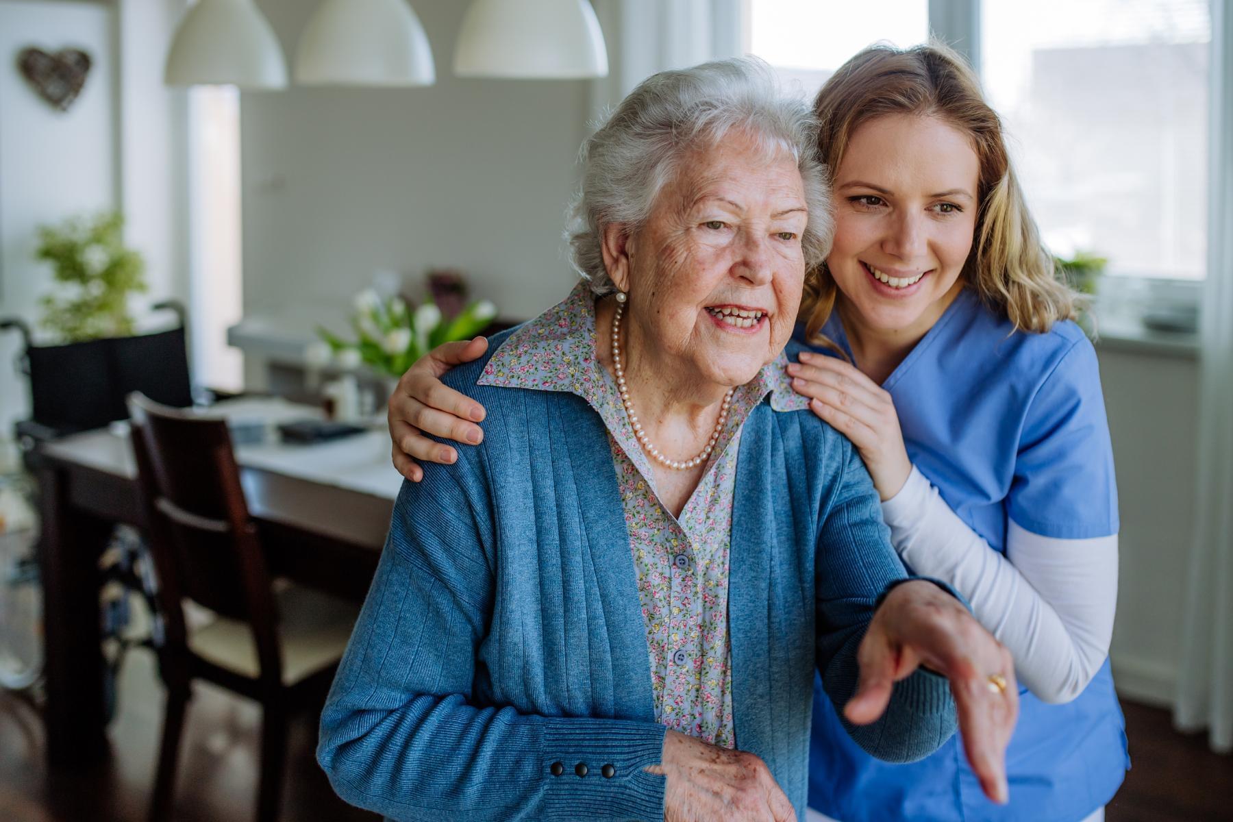 Elderly female resident and nurse at Benson House Care Home talking and looking into distance
