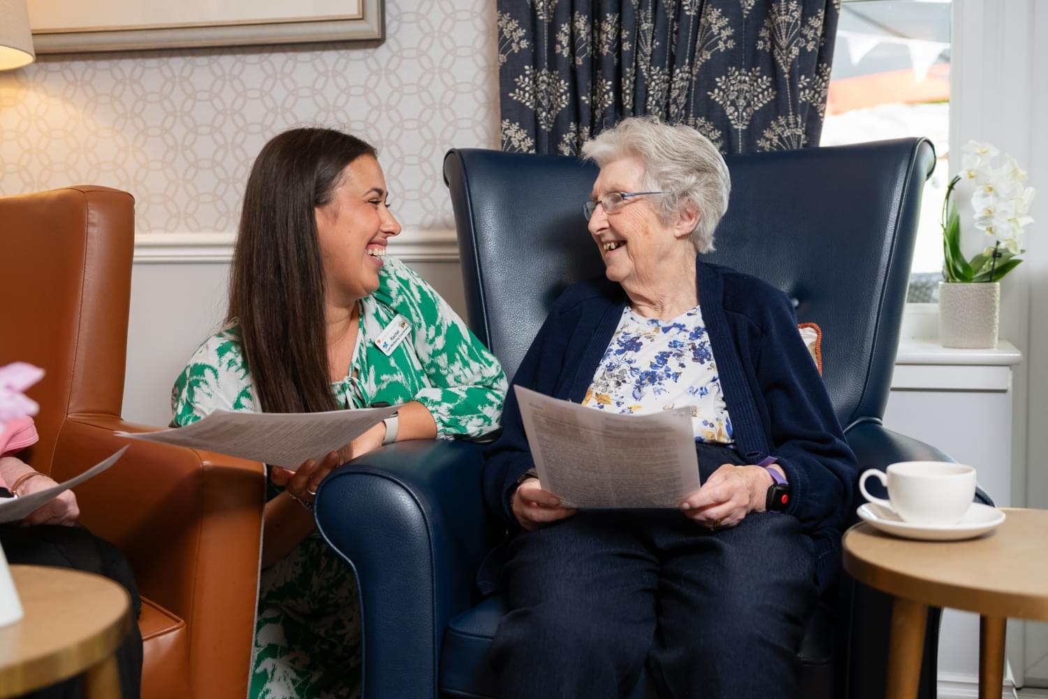 Activities person with resident song sheet laughing