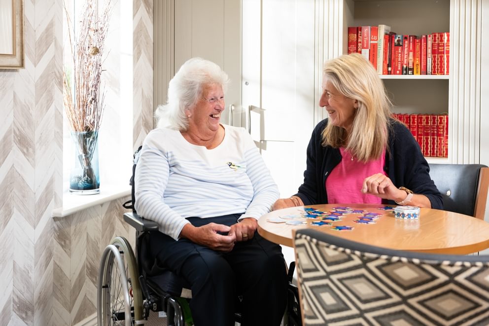 Resident and Activities doing a jigsaw smiling