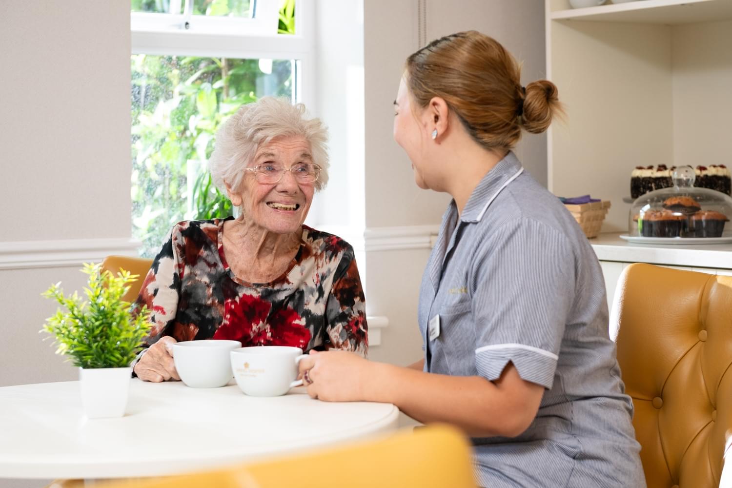 Resident with Carer in bistro chatting coffee cups