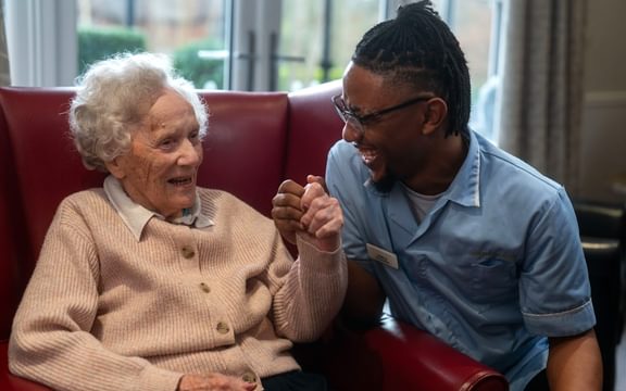Care Home carer at Horsell Lodge in Woking laughs with a resident.