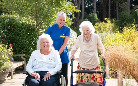 Two care home residents admire sunny gardens with the wellbeing co-ordinator