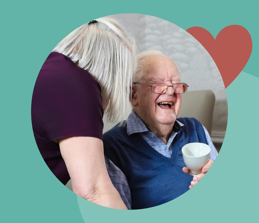 Patient living with dementia laughing with a carer in a care home