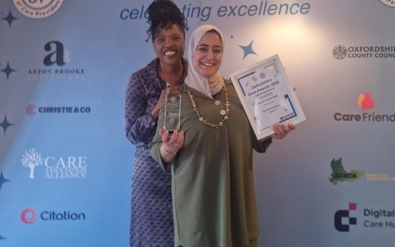 Care Home Wellbeing team member and Regional Manager with team member's award winning certificate