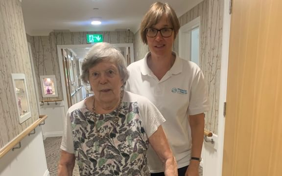 Resident and physiotherapist walking with a frame
