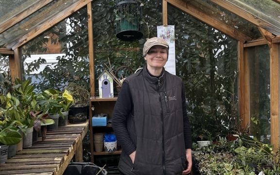 Gardener in greenhouse smiling at camera