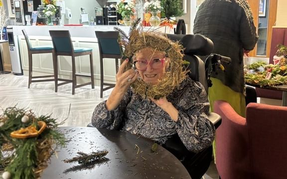 Care home resident peering through a hand-made wreath