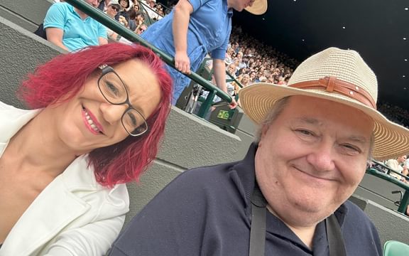 Red haired woman and man in hat at Wimbledon tennis tournament
