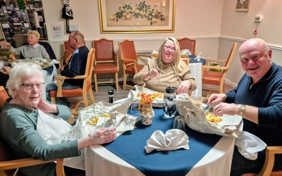 Care home residents enjoy fish & chips sitting round a table