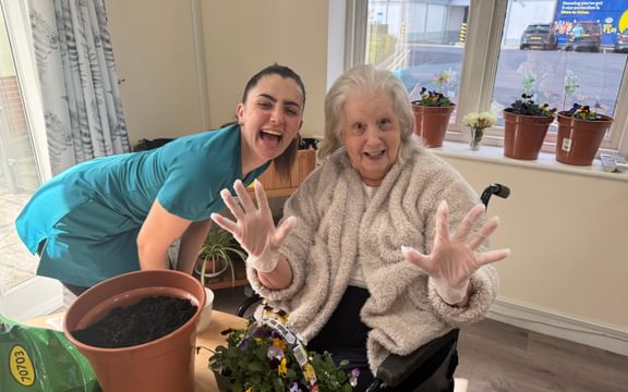 Resident and wellbeing team member laughing showing hands