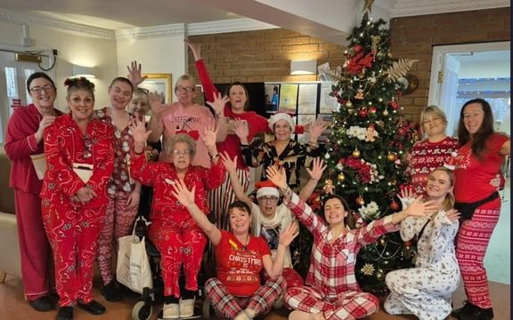 Group of care home staff and residents in Christmas pyjamas