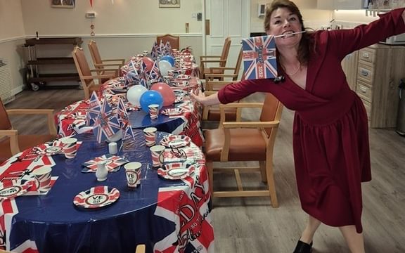 Woman in 1940s dress with flag next to VE Day decorated tables