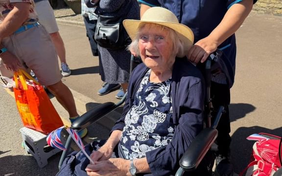 Care home resident Margery in blue with straw hat and union jack flag