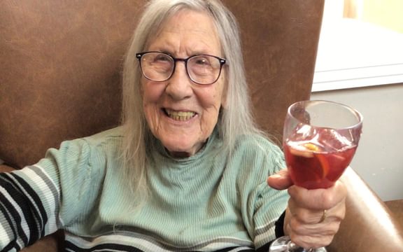 Care home resident smiling holding a glass of sangria
