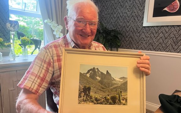 Care home resident with picture of Mount Kenya which he has climbed