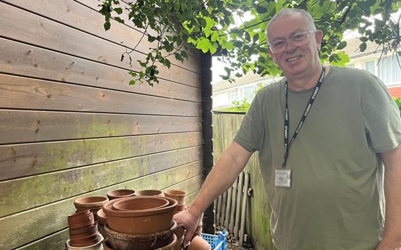 Care home gardener with a shelf full of pots