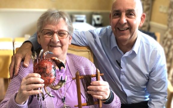 Care Home resident Betty with a Wellbeing Lead and a crab & yarn activity