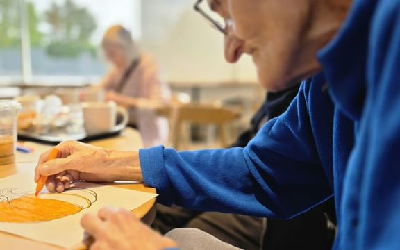Care home resident colours in a pumpkin sitting in a coffee shop