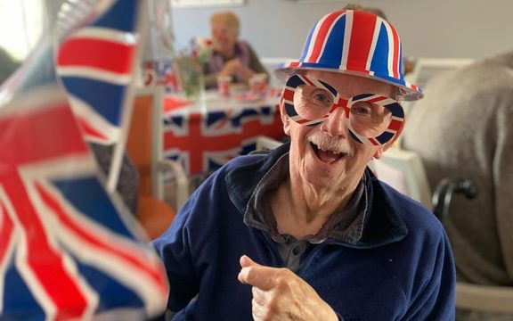 Care home resident celebrates VE Day with Union Jack hat, mask and flag