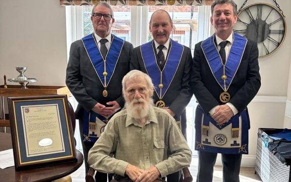 Bearded care home resident with three uniformed Masons and a certificate marking his 50 years as a Mason
