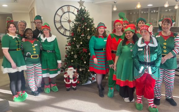 Care home team around a Christmas tree dressed as elves