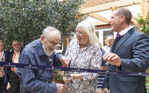 Care home resident cuts ribbon with giant scissors