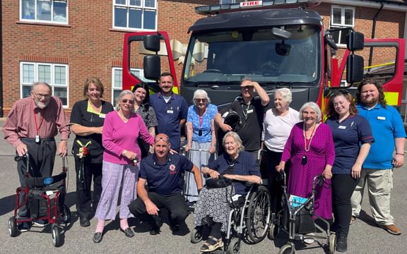 Care home team and residents pose with firefighters in front of their fire truck