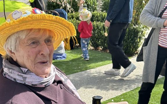 Resident in purple coat wearing yellow Easter bonnet