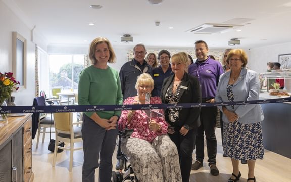 Care home resident posed to cut the ribbon at a launch event