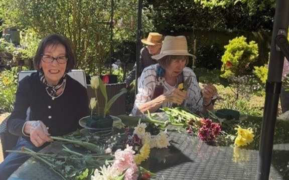 Two residents arranging flowers on a table in the garden