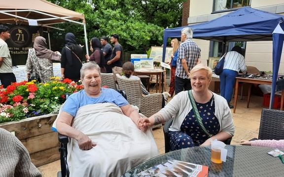 Resident in wheelchair and friend at summer barbecue