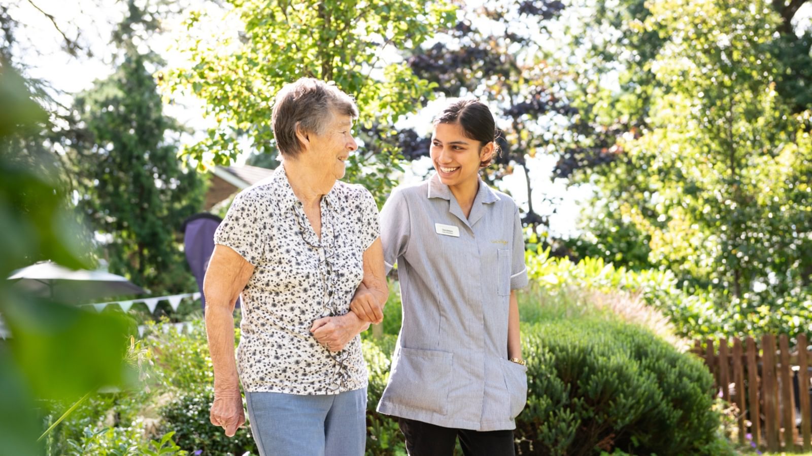 Resident walking in a care home with a carer