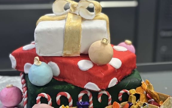 Christmas cake in the shape of a pile of presents with baubles surrounded by an edible train and carriages