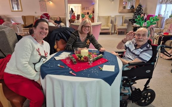 Care home resident wearing costume antlers enjoying a Christmas lunch with family members