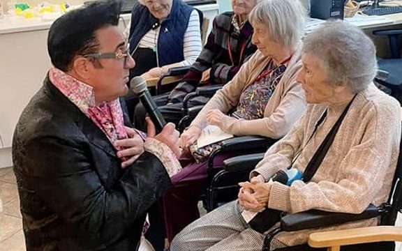 Elvis impersonator kneels and sings to care home resident