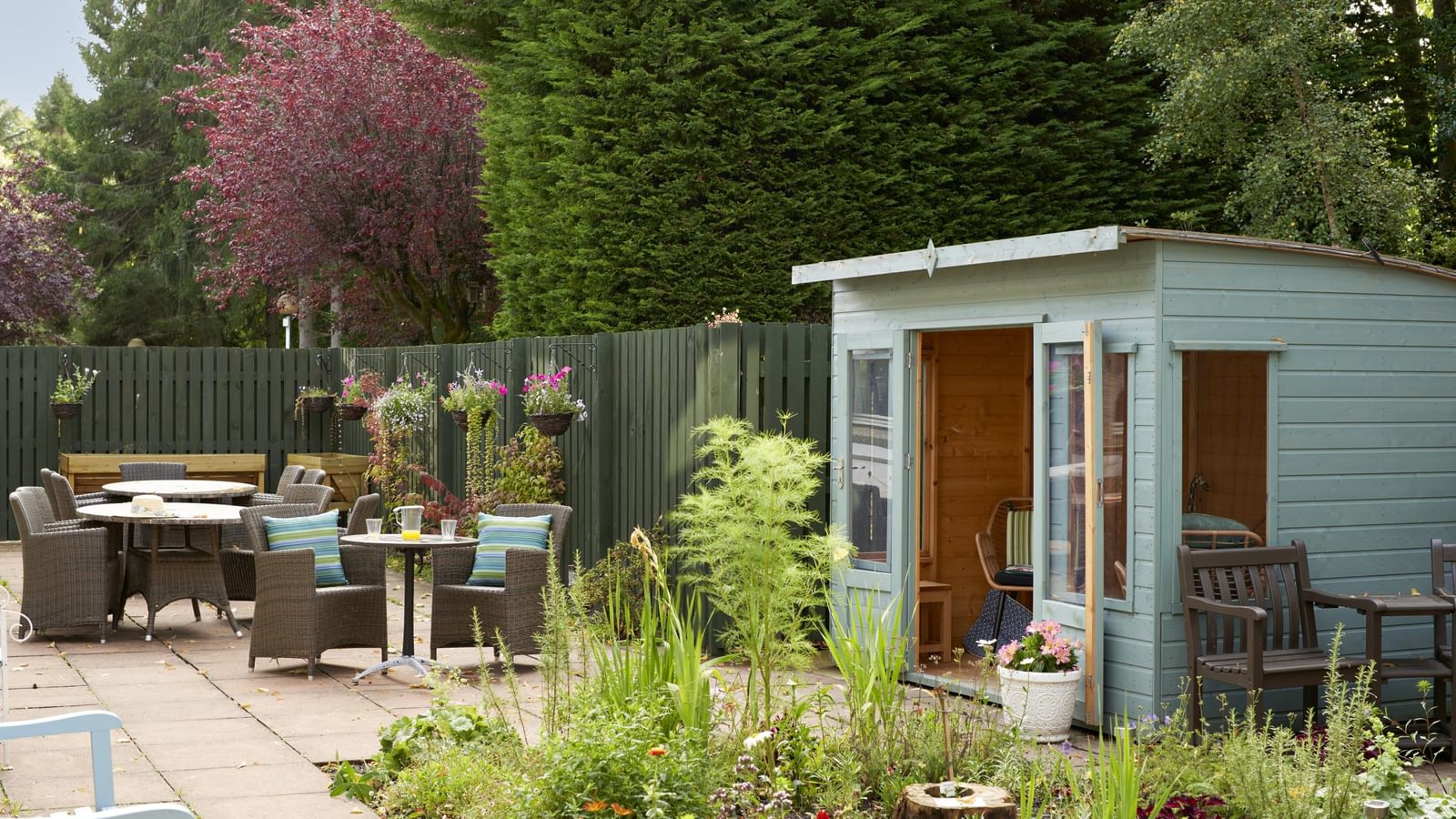 Hawkhill House garden area decorated with plants, seating and a turquoise-coloured shed