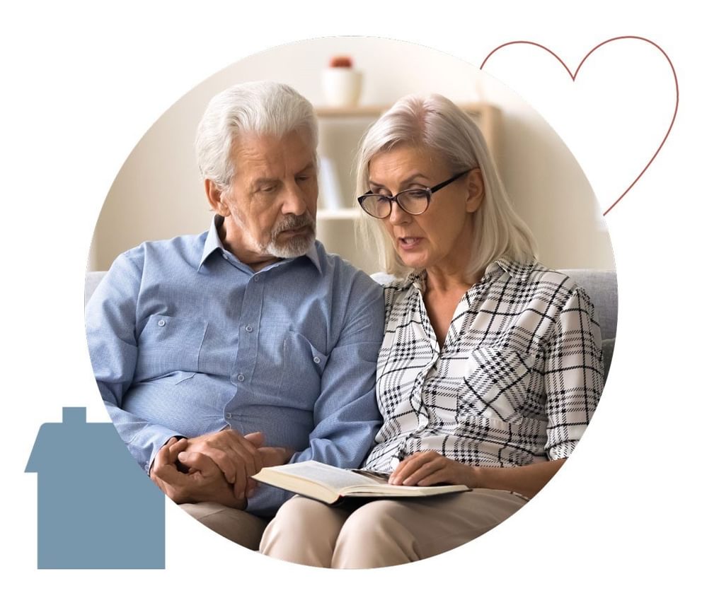 Two people in a dementia care facility read together on a sofa