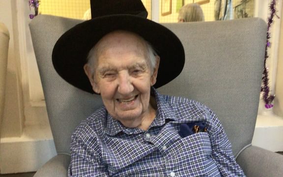Male care home resident laughs wearing a witches hat to celebrate Halloween