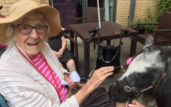 Smiling resident petting a pony