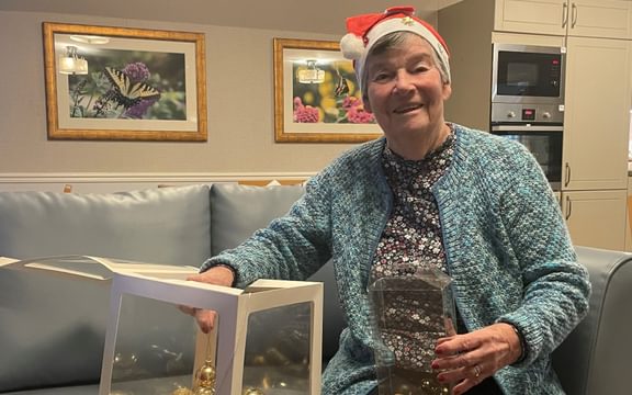 Care Home resident assembles Christmas baubles inside a clear box