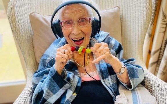 Care home resident smiles before eating a healthy fruit stick
