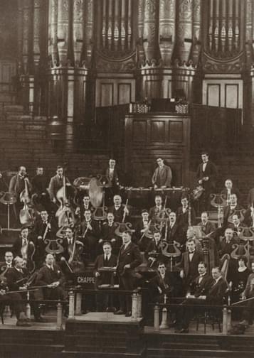 Old black and white photograph of the orchestra's founding members in 1920, in front of the organ at Birmingham Town Hall