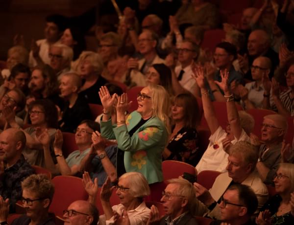 A photograph of a woman giving a standing ovation in Symphony Hall
