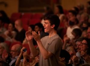 Photograph of a young man giving a standing ovation in Symphony Hall